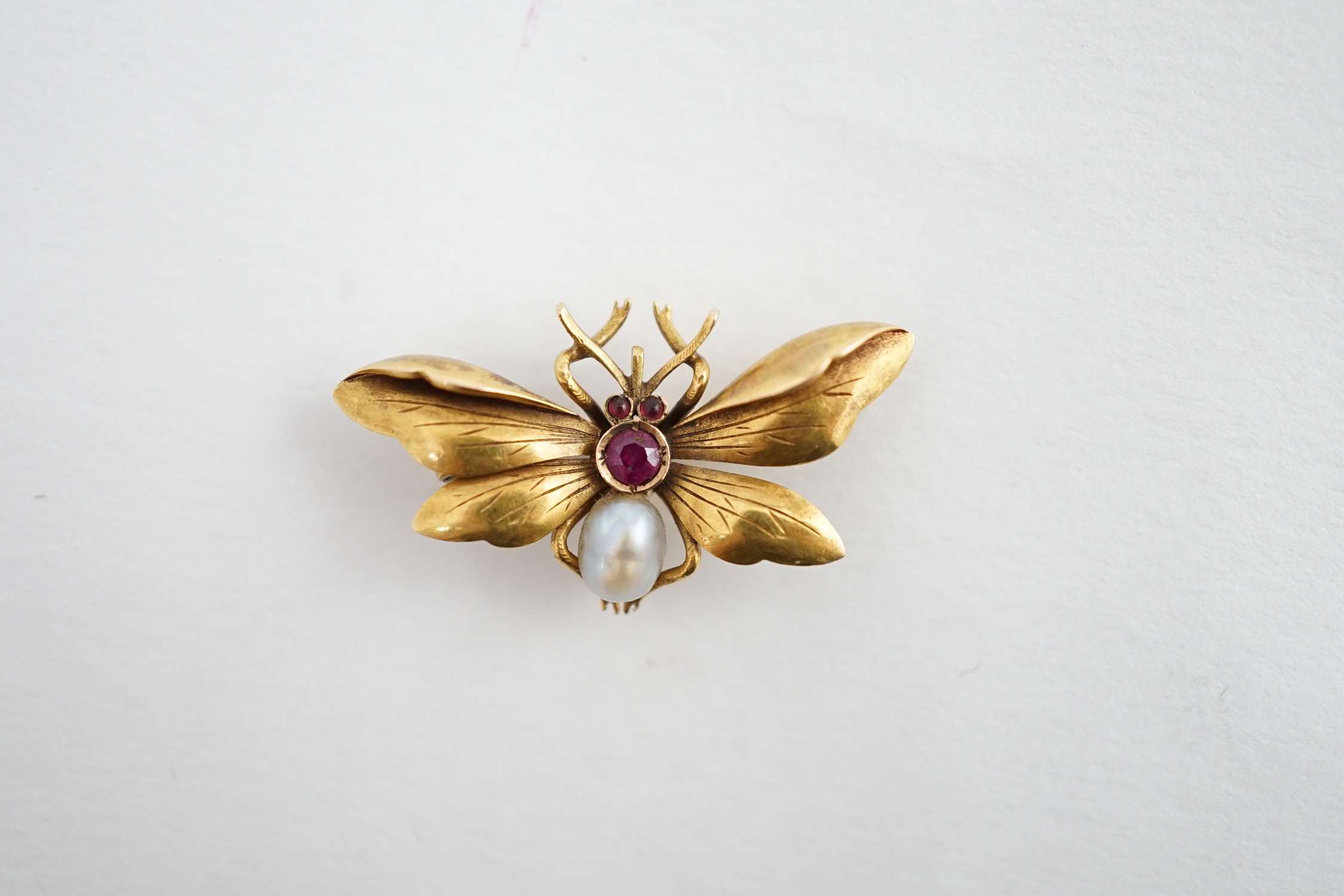 An early 20th century gold (stamped 18), ruby and baroque pearl set bug brooch